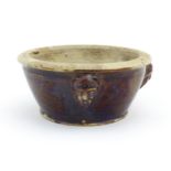 A stoneware bowl with a treacle glaze and three relief masks to side. Approx. 3" high x 6 1/2"