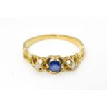 A yellow metal ring set with central sapphire flanked by diamonds. Ring size approx. J Please Note -