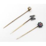 Three assorted yellow and gilt metal stick pins to include examples set with diamonds and white