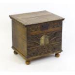 An 18thC and later oak log box with a carved and hinged lid above a carved front panel with armorial