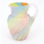 A glass jug with pink, yellow blue and orange swirl detail , with clear loop handle. Approx 8 1/2"