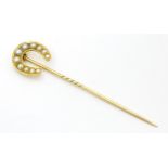 A Victorian yellow metal stick pin surmounted by a horseshoe set with graduated pearl detail. 3 1/4"