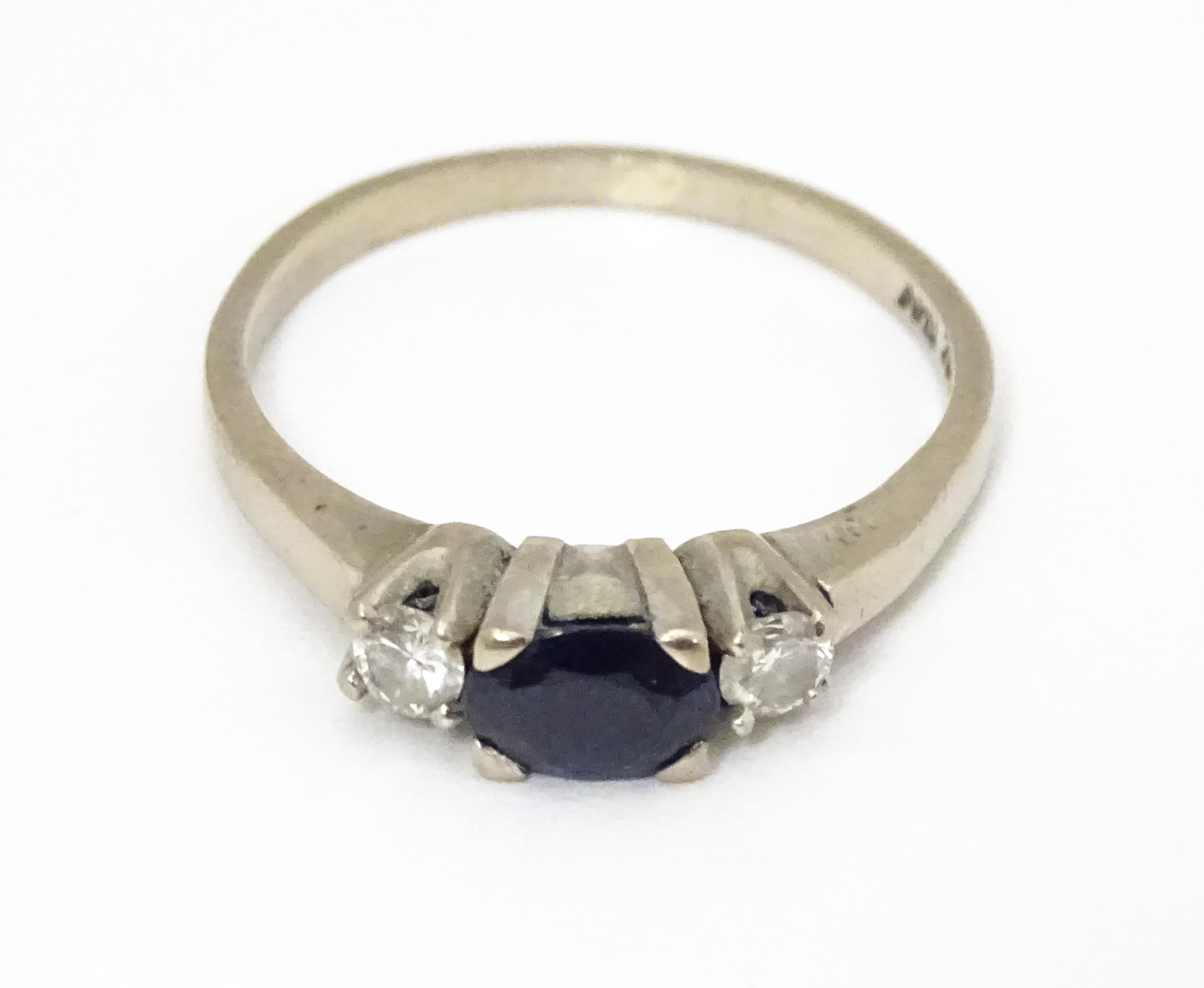 An 18ct white gold ring set with central sapphire flanked by diamonds. Ring size approx. M 1/2