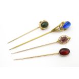 Four assorted yellow and gilt metal stick pins set with various coloured cabochon. Largest approx.