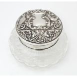 A cut glass powder pot with silver lid having embossed decoration and mirror under. Hallmarked