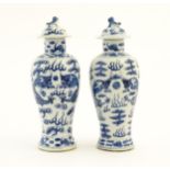 A pair of Chinese blue and white lidded vases decorated with dragons and a flaming pearl amongst