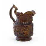 A treacle glazed jug with monkey and mask detail. Approx. 6 1/2" high Please Note - we do not make