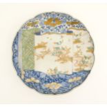 A Japanese dish with shaped rim decorated with scroll decoration depicting flowers, foliage, and