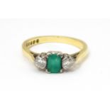 An 18ct gold ring set with central emerald flanked by diamonds. Ring size approx K 1/2 Please Note -