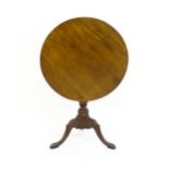 A George III mahogany tripod table with a circular reeded top above a turned pedestal and three well
