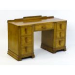 An Art Deco oak desk / dressing table with a shaped upstand, inverted breakfront top and fluted
