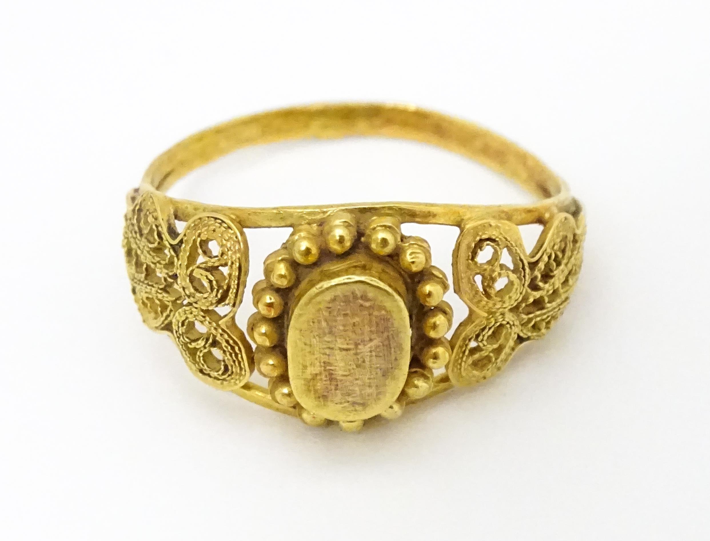 A yellow metal ring with filigree decoration. Ring size approx. K 1/2 Please Note - we do not make