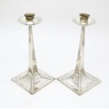 A pair of Arts and Crafts silver candlesticks of tapering square form, circular capitals and drip