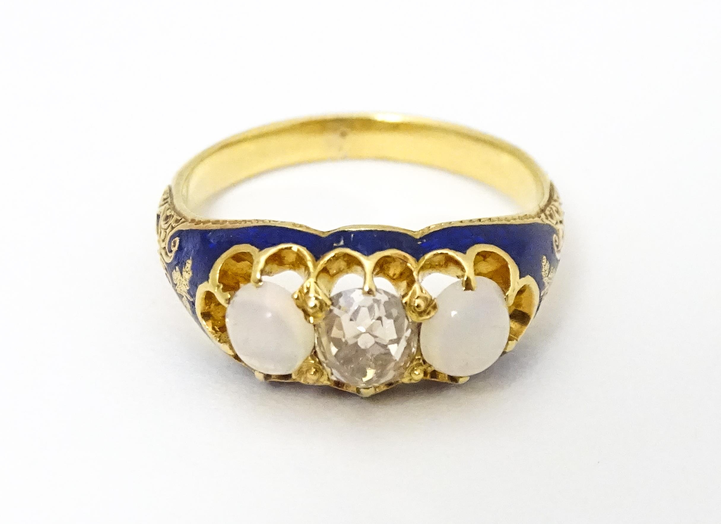 A 19thC yellow gold ring set with central diamond flanked by opals in a blue enamel setting. Ring