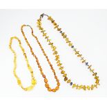 Three various amber coloured bead necklaces. The longest also set with lapis lazuli beads. Approx