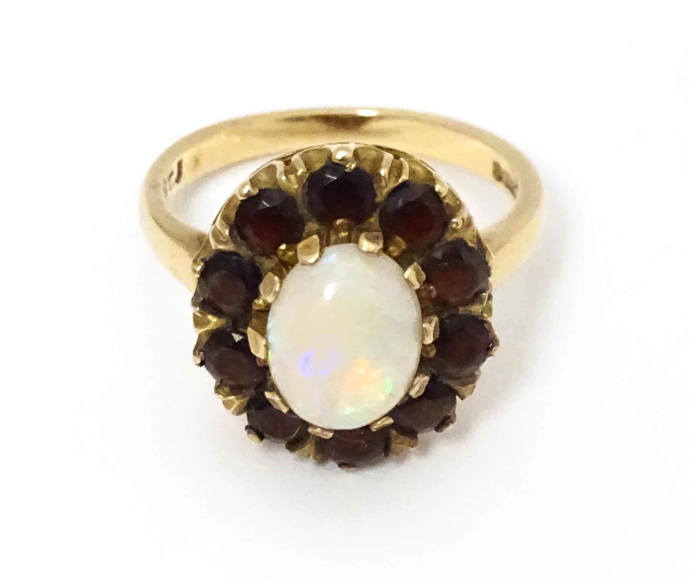 A 9ct gold ring set with central opal bordered by garnets. Ring size approx. L Please Note - we do