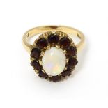 A 9ct gold ring set with central opal bordered by garnets. Ring size approx. L Please Note - we do