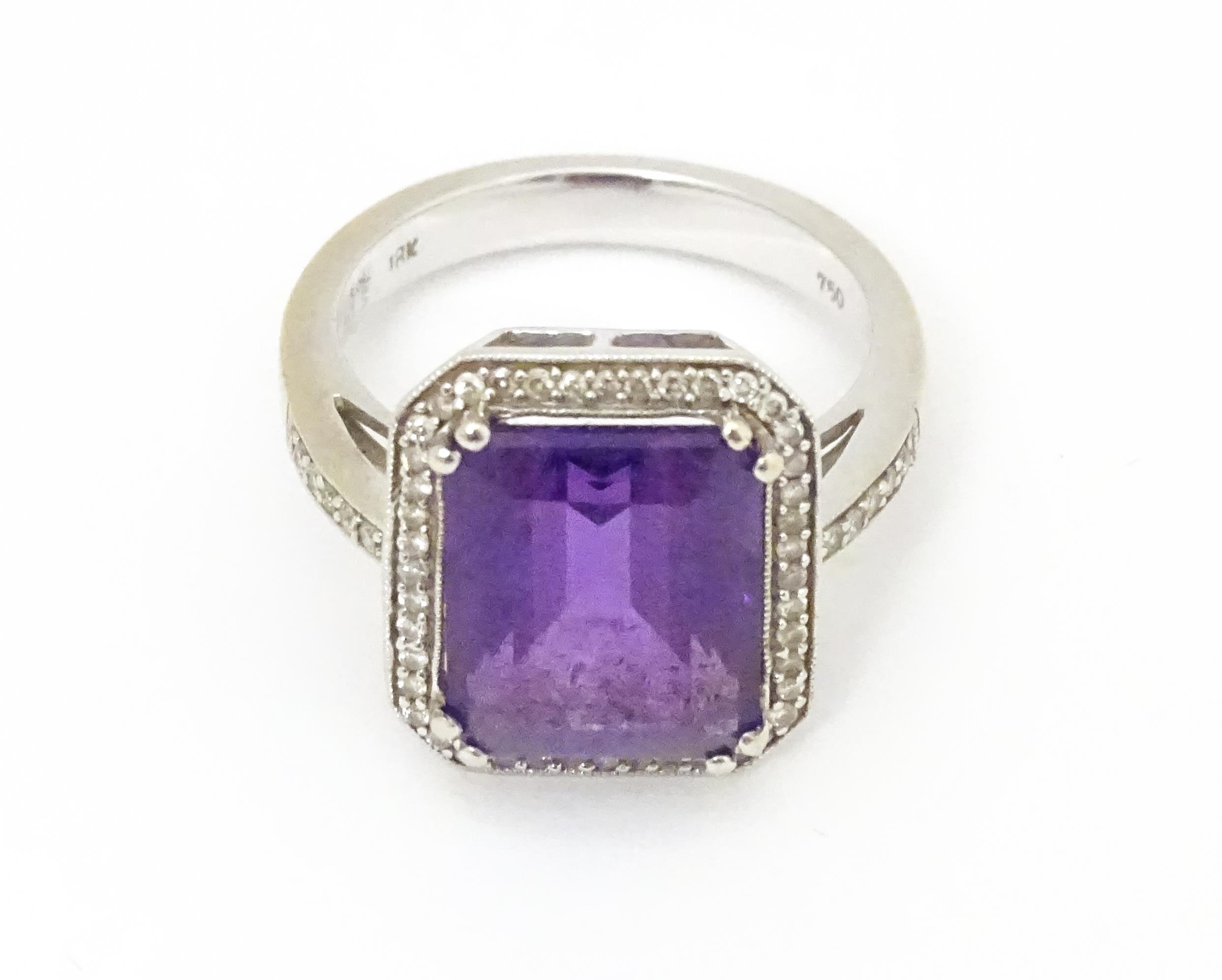 An 18ct gold ring set with central amethyst bordered by diamonds with further diamonds to shoulders.