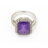 An 18ct gold ring set with central amethyst bordered by diamonds with further diamonds to shoulders.