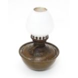 An early 20thC oil lamp, the brass weighted base with reservoir, screw-in burner and white glass