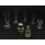 Four glass measuring flasks of tapering form, a glass smelling salts bottle and an eyebath.