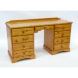 A pine double pedestal desk with a moulded top and a shaped upstand, having two banks of four
