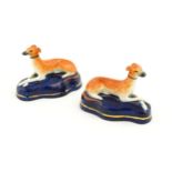 A pair of Staffordshire pottery models of reclining greyhounds / dogs. Approx. 3 1/2" wide (2)