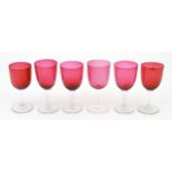 Six assorted cranberry glass drinking glasses, with cranberry coloured bowls and clear glass stem