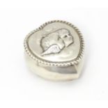 A Victorian silver pill box of heart shape with hinged lid and embossed angel / cherub detail to