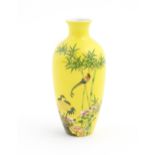 A Chinese vase with a yellow ground decorated with birds, flowers, bamboo and foliage. Character