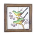 Four hand painted tiles framed together depicting two birds perched on a branch with blossom. Signed