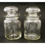 Two glass jars and stoppers decorated with etched fruiting vine detail. Approx 5 3/4" high (2)