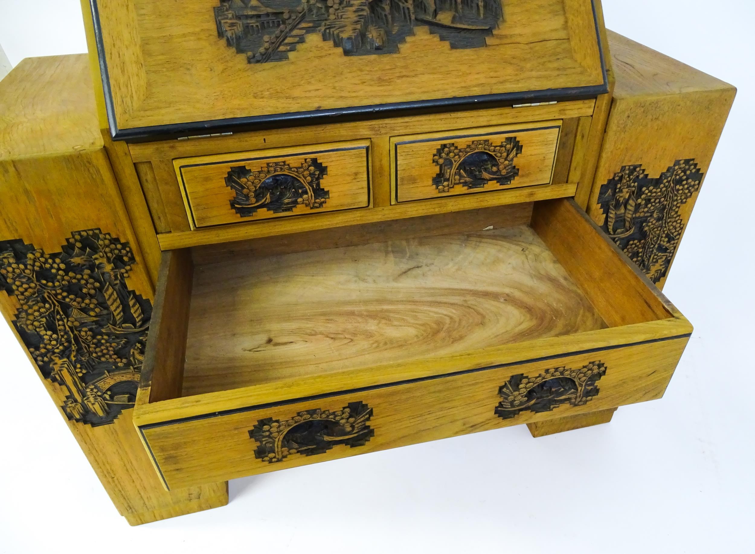 An early / mid 20thC Teak bureau accompanied by a stool, with carved oriental scenes to the front, - Image 7 of 12