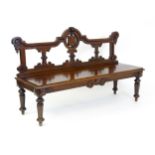 A Victorian mahogany bench, with a shaped top rail, carved terminals and an armorial shield to the