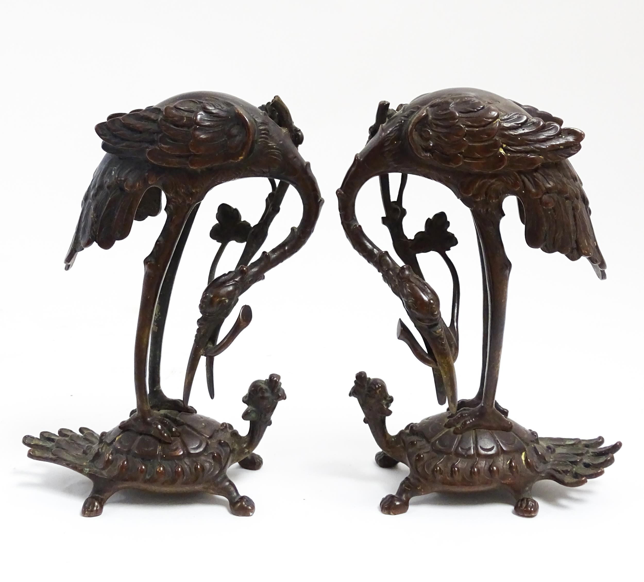 A pair of Japanese cast sculptures modelled as a stylised crane standing on a tortoise. Approx. 7