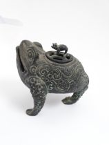 A Chinese cast censer modelled as a three legged toad with scrolling decoration, the pierced lid