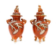 A pair of Japanese Kutani lidded vases with twin foo handles and raised on three feet, the body