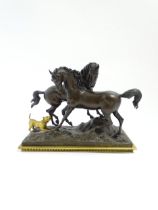 A 20thC cast bronze sculpture depicting two horses with a gilt dog barking at them, on a