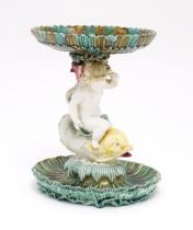 A 19thC majolica tazza / centrepiece bowl, the figural stem with a cherub / putto riding a dolphin