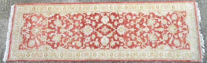 Carpet / Rug : A salmon red ground Runner with beige border, decorated with floral and foliate