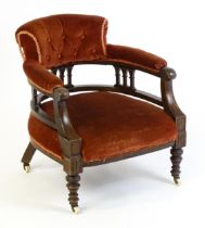An early 20thC bow back armchair, with deep buttoned upholstery and raised on turned tapering