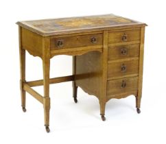 An Arts & Crafts oak desk, with an inset leather top above a bank of four graduated drawers and