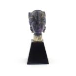 A 20thC amethyst carving modelled as a male head with headdress, mounted on a tapering plinth.