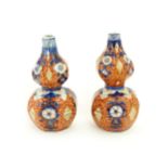 A matched pair of Japanese double gourd vases decorated in the Imari palette with floral motifs