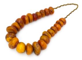 A necklace of graduated amber coloured beads. Smallest approx. 1 1/4" diameter, Largest bead approx.