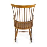 A mid 19thC ash and sycamore Windsor rocking chair, with a bowed top rail, tuned spindles and a