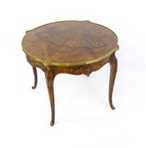 A late 19thC / early 20thC walnut centre table with a shaped top and a gilt surround, the table