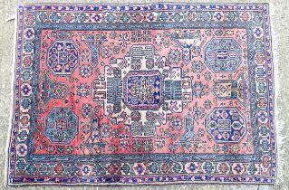 Carpet / Rug : A salmon pink ground rug with geometric and floral motifs and borders worked in