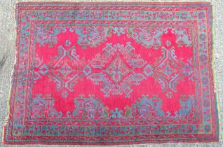 Carpet / Rug : A red ground rug decorated with floral, foliate and geometric detail worked in blue