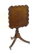 A late Georgian mahogany tripod table with a carved pie crust style top, a coil style turned